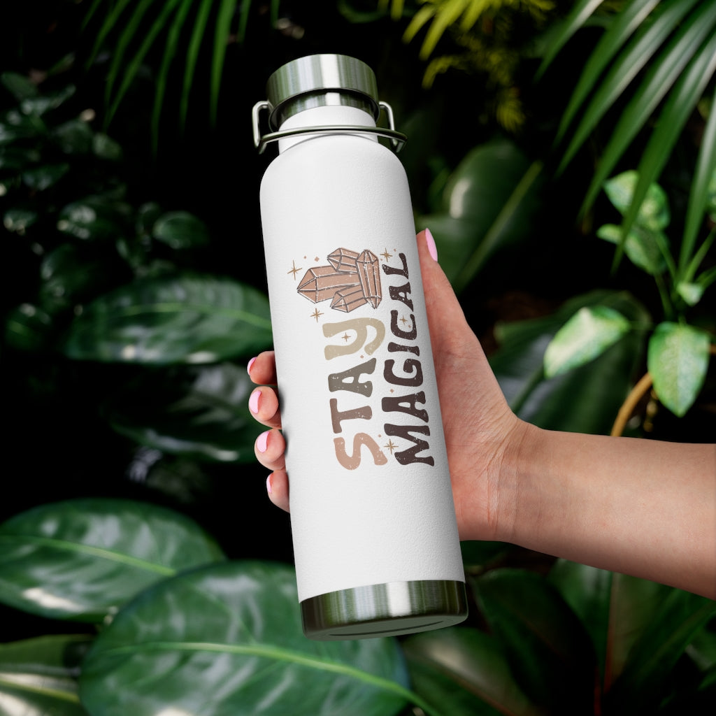 View of the white insulated bottle against a tropical foliage background in the palm of a model. 