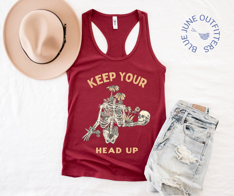 Super soft women's slim racerback tank top in cardinal red. This tank is from Blue June Outfitters exclusive Morbid Nature Collection and features a skeleton wrapped in plants and wildflowers holding his on skull up with his hand. The phrase keep your head up is printed. Perfect for those who appreciate dark humor!