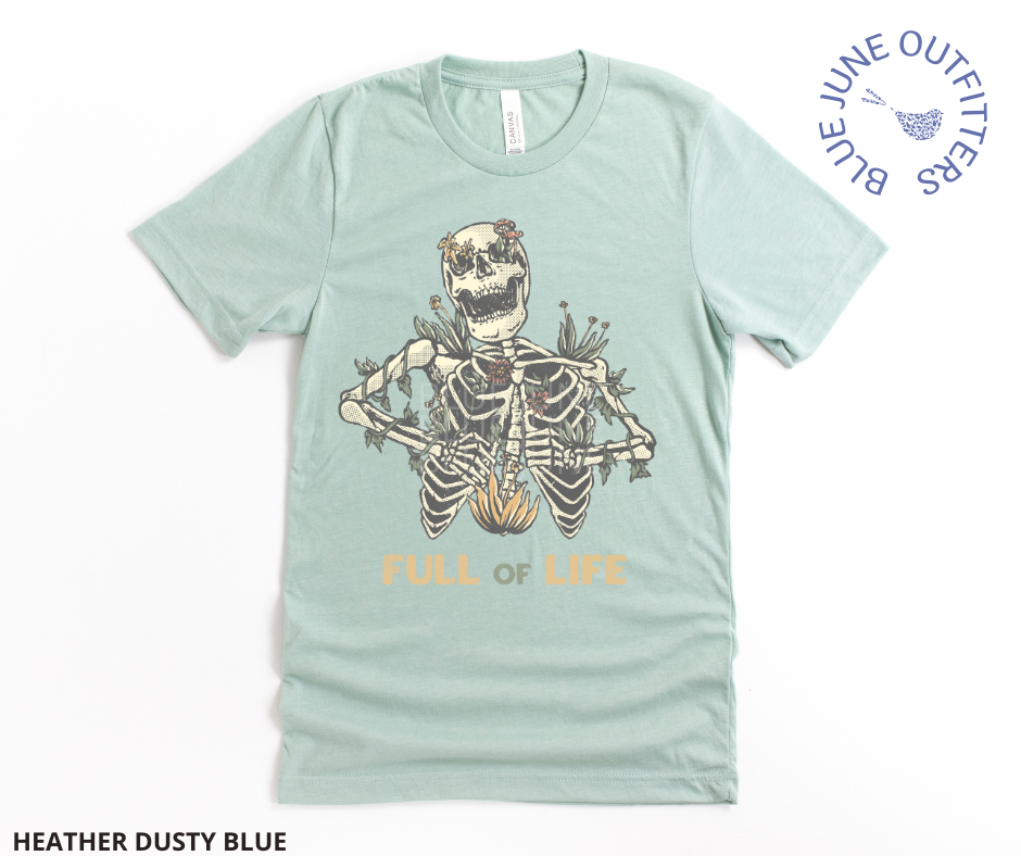 Super soft Bella + Canvas brand shirt in heather dusty blue. This tee is from Blue June Outfitters' exclusive Morbid Nature Collection. It features a skeleton covered in plants has the phrase full of life underneath.