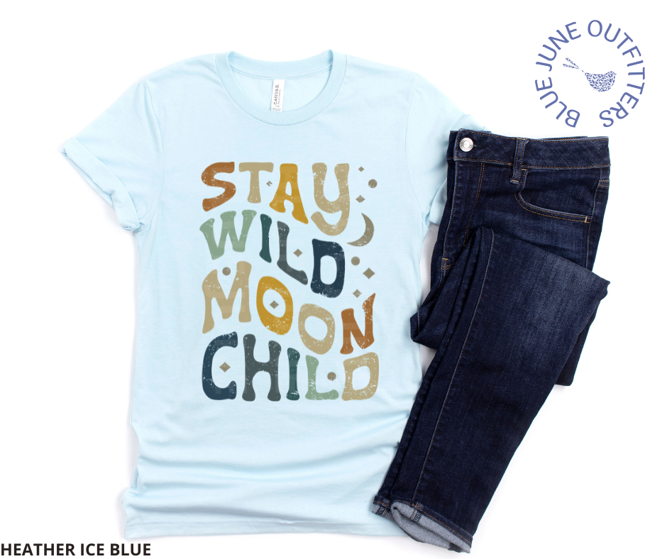 Unisex Bella + Canvas tee in heather ice blue. This shirt is from our exclusive Hippie Collection and features wavy, hippy letters that rea stay wild moon child. There are also small stars and a crescent moon intermixed with the lettering. The colors of the text are a mix of dark blue, earthy green, mustard yellow and rust. Shown here with a pair of dark blue jeans. 