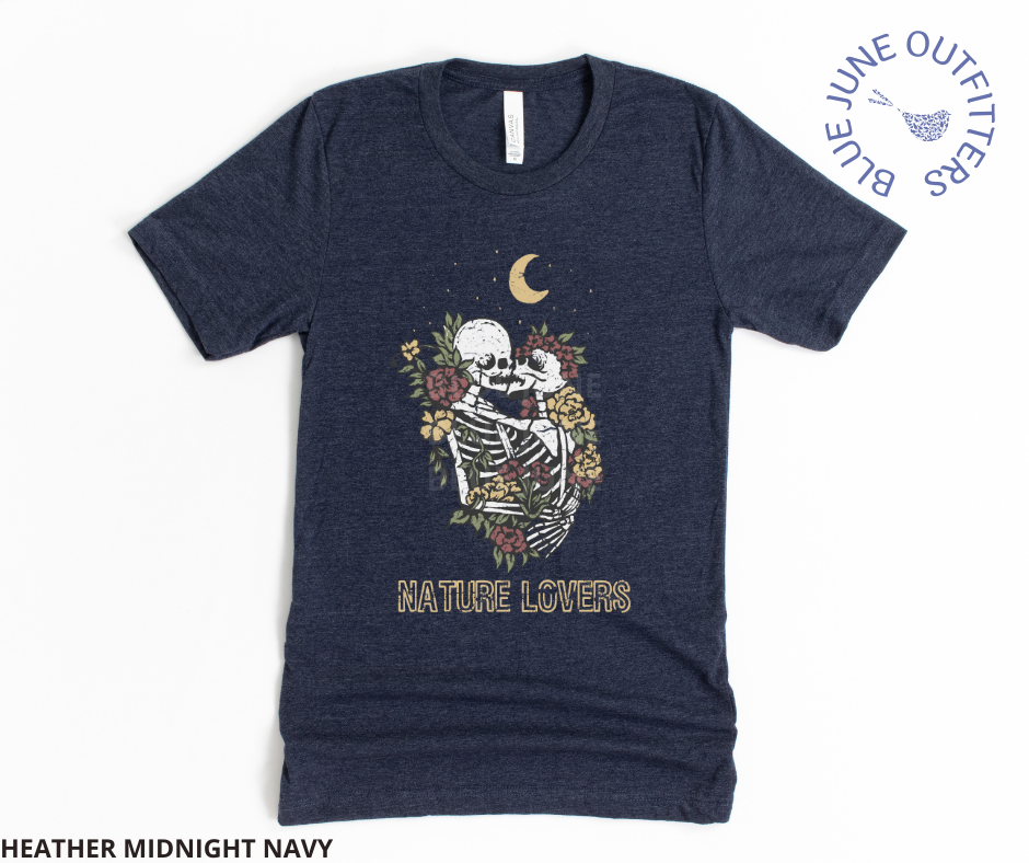 Super soft Bella + Canvas brand tee in heather midnight navy. This shirt from Blue June Outfitters' exclusive Morbid Nature Collection features two skeletons in a loving embrace wrapped in nature under the crescent moon that reads nature lovers at the bottom. This is our take on the lovers tarot card.