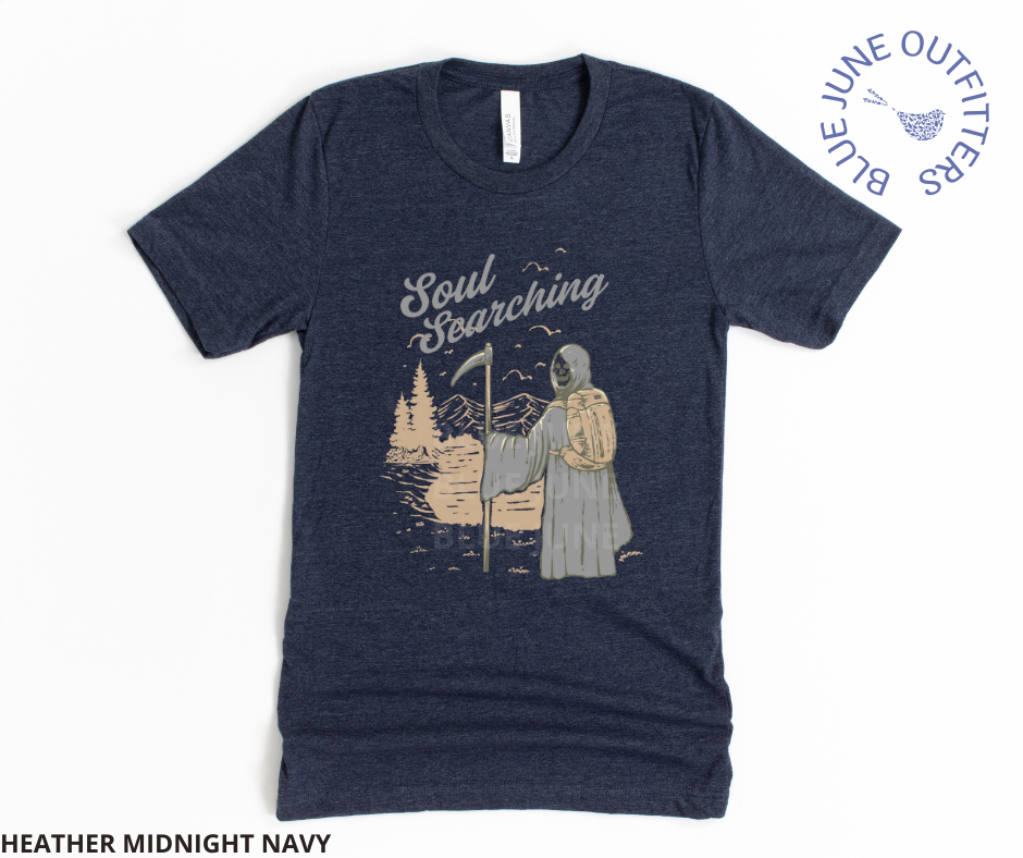 Super soft Bella + Canvas brand tee in heather midnight navy. This shirt from Blue June Outfitters' exclusive Morbid Nature Collection features the grim reaper backpacking in nature. The phrase soul searching is printed above. Perfect for those who appreciate dark humor!