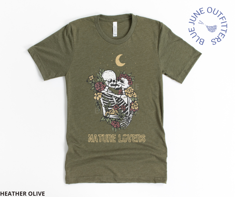 Super soft Bella + Canvas brand tee in heather olive. This shirt from Blue June Outfitters' exclusive Morbid Nature Collection features two skeletons in a loving embrace wrapped in nature under the crescent moon that reads nature lovers at the bottom. This is our take on the lovers tarot card.