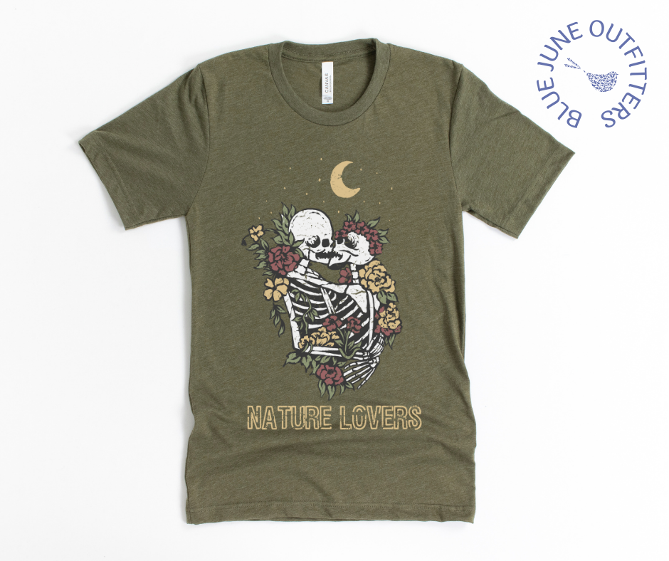 Super soft Bella + Canvas brand tee in heather olive. This shirt from Blue June Outfitters' exclusive Morbid Nature Collection features two skeletons in a loving embrace wrapped in nature under the crescent moon that reads nature lovers at the bottom. This is our take on the lovers tarot card.