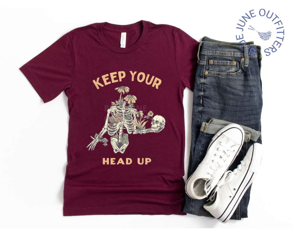 Super soft Bella + Canvas tee in maroon.  This shirt from Blue June Outfitters' exclusive Morbid Nature Collection features a skeleton covered in plants holding his skull up in his hands with the phrase keep your head up. This is the perfect tee for those who share 