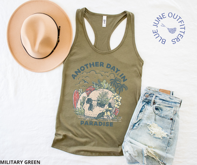 Super soft women's slim fit racerback tank top in military green. Paired here with jean shorts and a trendy hat. This tank is from Blue June Outfitters' exclusive Morbid Nature Collection and features a skull on the beach with palm trees, tropical plants, seagulls and surf boards. The text reads another day in paradise.