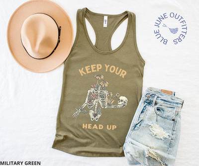 Super soft women's slim racerback tank top in military green. This tank is from Blue June Outfitters exclusive Morbid Nature Collection and features a skeleton wrapped in plants and wildflowers holding his on skull up with his hand. The phrase keep your head up is printed. Perfect for those who appreciate dark humor!