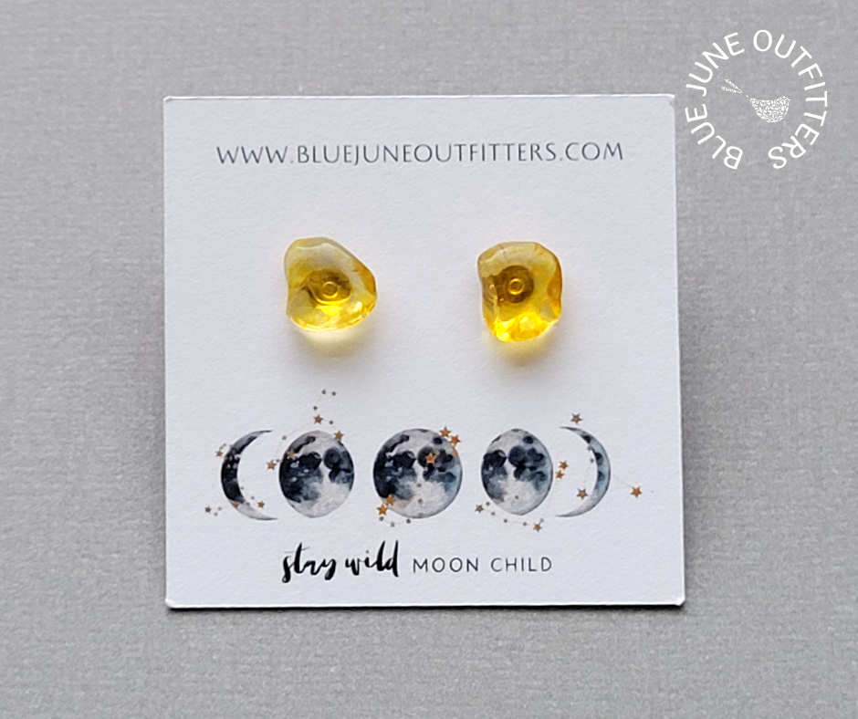 View of another set of citrine stud earrings on the earring card. This is a closer view. They are a vibrant golden yellow and slightly translucent. 