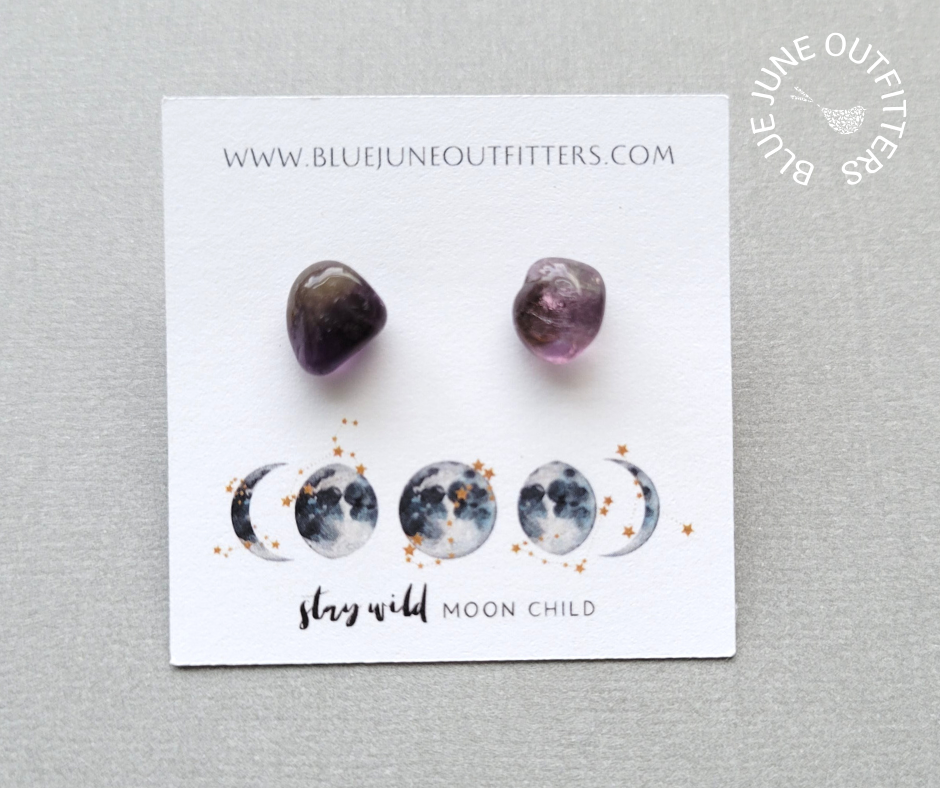 View of another set of amethyst stud earrings on the earring card. This is a closer view. They are dark and light purple coloring.
