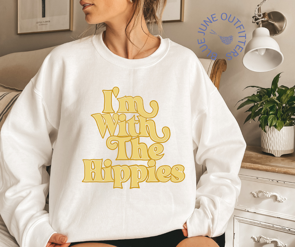Model wearing the white oversized crewneck sweatshirt. The text is a mustard yellow, retro wavy font that reads I'M WITH THE HIPPIES.