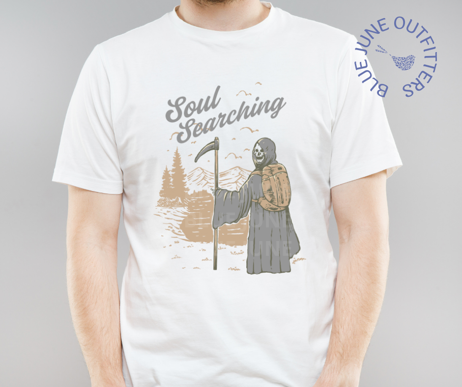 Super soft Bella + Canvas brand tee in white. This shirt from Blue June Outfitters' exclusive Morbid Nature Collection features the grim reaper backpacking in nature. The phrase soul searching is printed above. Perfect for those who appreciate dark humor!