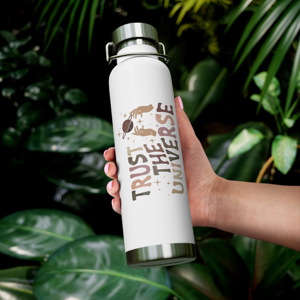 The white insulated bottle with lid shown here with a tropical foliage background, being held in the palm of a model. 