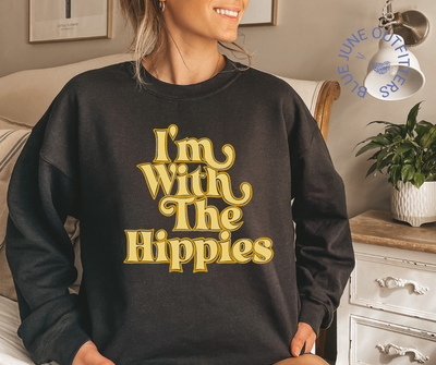 Model wearing the black oversized crewneck sweatshirt.  The text is a mustard yellow, retro wavy font that reads I'M WITH THE HIPPIES. 
