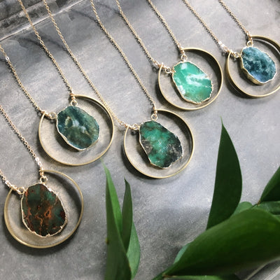 View of five different pendants that demonstrate the variations in color and shapes of the gemstones. 