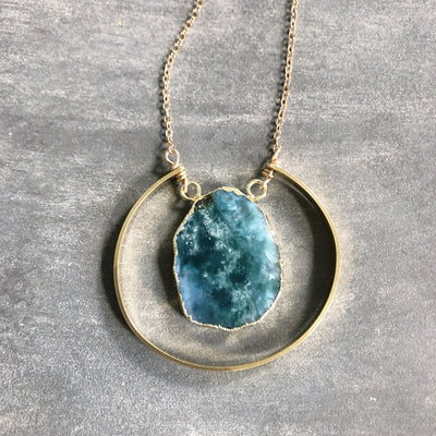 Beautiful blue green raw chrysoprase slice pendant surrounded by gold electroplating. It is encompassed by a brass semi-circle accent. The chain is 30" with a 2" extender and is hypo allergenic gold plated.