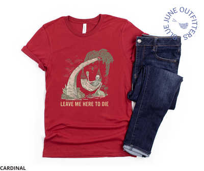 Super soft Bella + Canvas brand tee in cardinal paired next to a pair of dark blue jeans. This shirt from Blue June Outfitters' exclusive Morbid Nature Collection features a skeleton holding a beer in a hammock, camping on the beach. Underneath it reads leave me here to die. Perfect camping tee for those with a dark sense of humor!